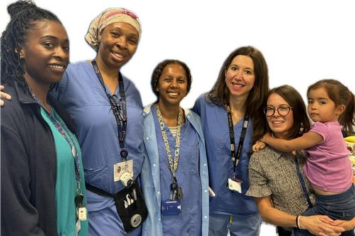 Group photo of smiling maternity triage team members with a young child guest, standing together